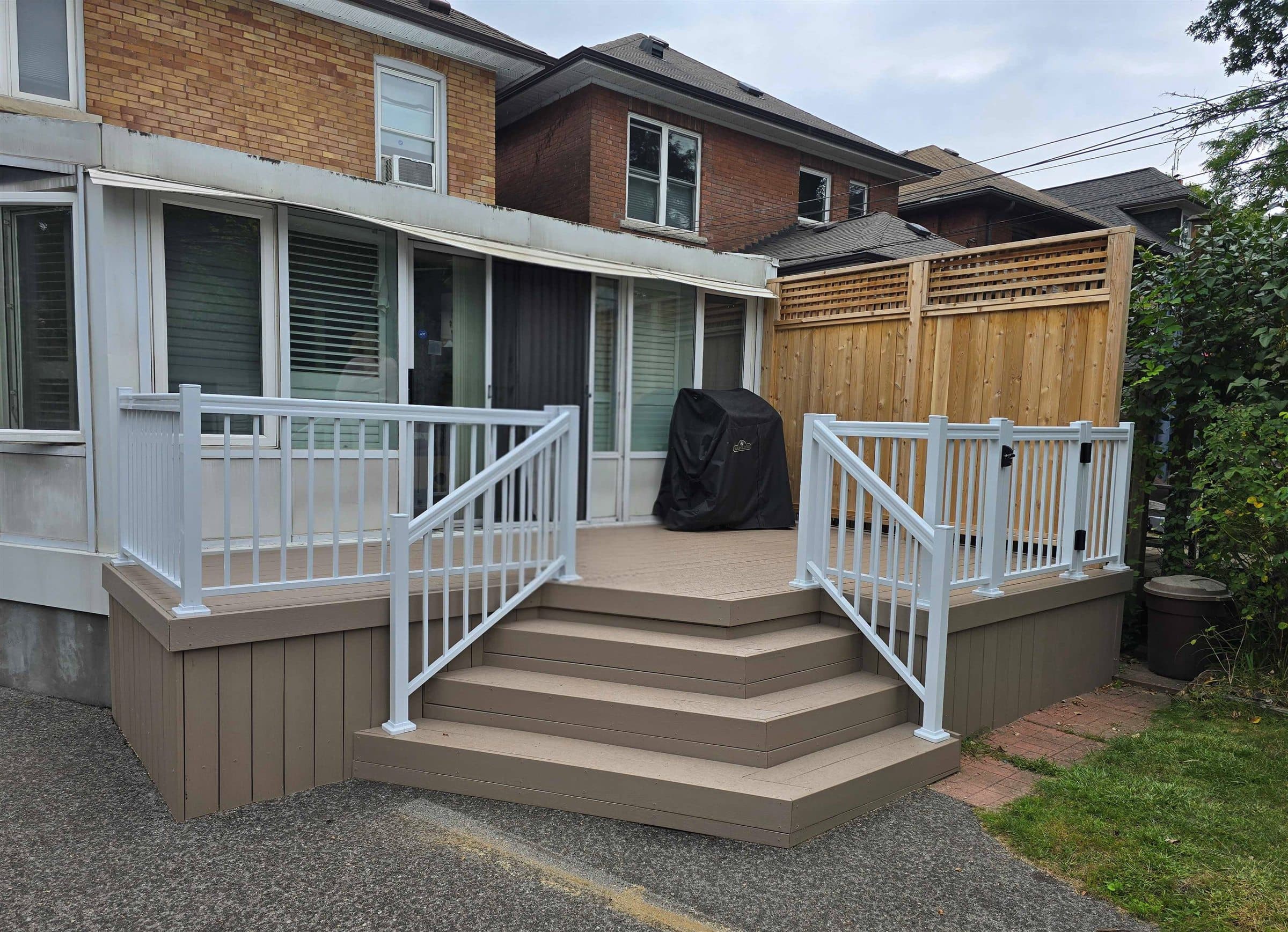Composite deck with white railings, a gate and a new cedar privacy fence
