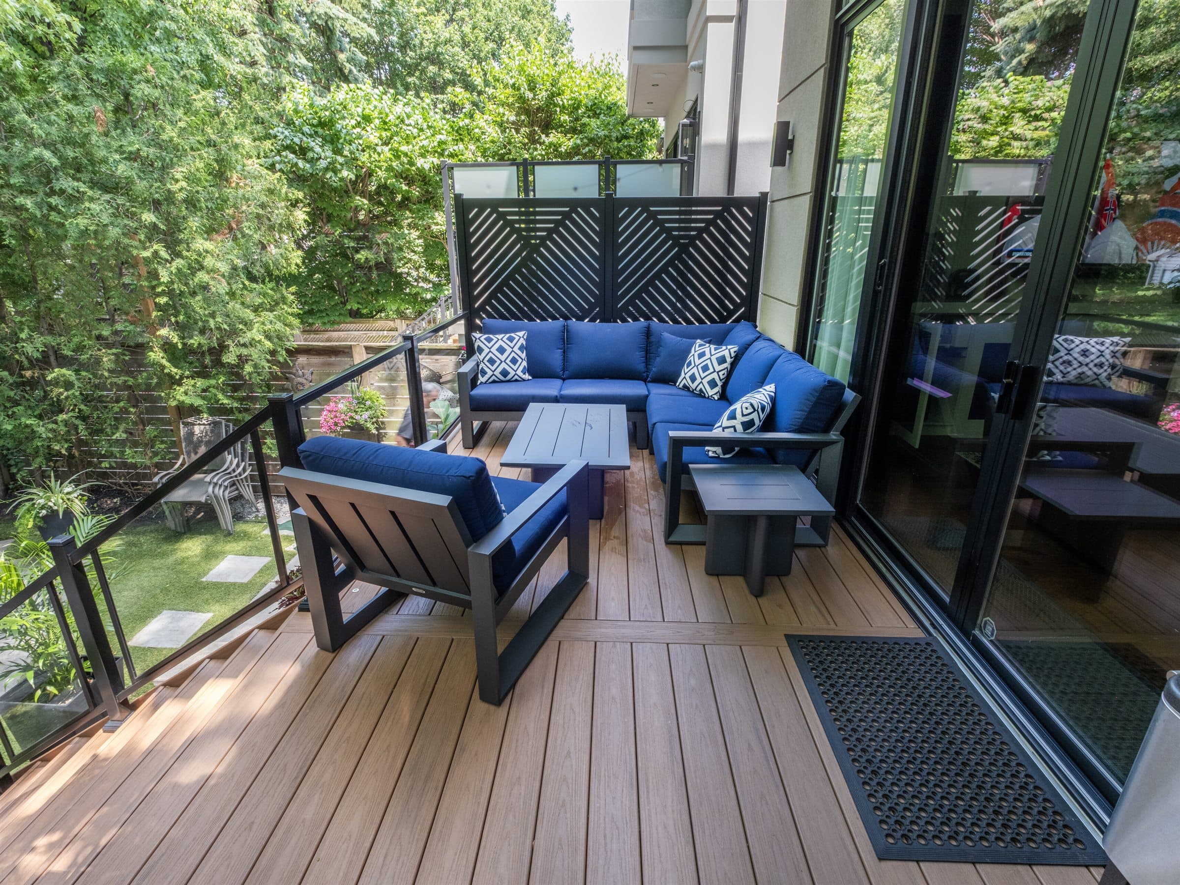 Composite deck lounge area with glass railings and a black privacy screen on a Toronto West home